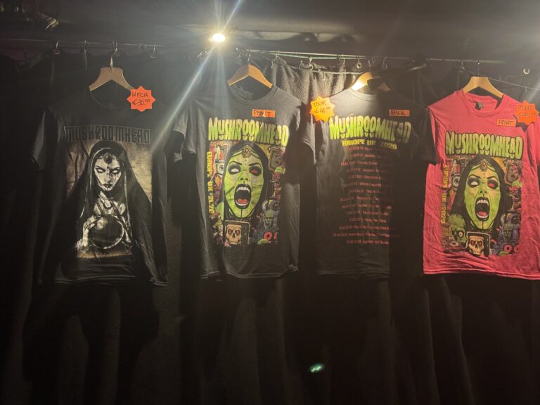 Tekst alternatywny Koszulki Mushroomhead z komiksowymi wizerunkami Jackie LaPonzy na stoisku z merchem we Wrocławiu